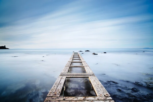 Dřevěné molo nebo mola na modrý oceán v noci. Dlouhé vystavení — Stock fotografie