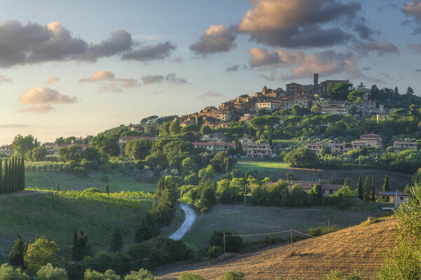 View of the medieval Casale Marittimo village perched on a hill above rolling Tuscan fields at sunset, Tuscany, Italy