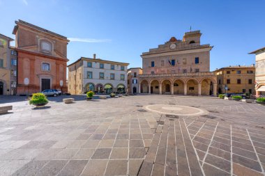 Montefalco, Umbria 'nın ortaçağ tepe kasabasının merkezi meydanı Piazza del Comune manzarası. Mavi gökyüzünün altındaki tarihi Palazzo Comunale 'i sunar. İtalyan seyahat sahnesi.