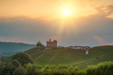 Langhe tepeleri üzerinde dramatik bir gün batımı, Piedmont, İtalya. Ortaçağ Grinzane Mağara Şatosu teraslı üzüm bağlarıyla çevrili bir tepenin üzerinde duruyor. Unesco Şarap Bölgesi.