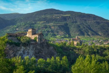 İtalya 'nın Aosta Vadisi manzarası, iki ortaçağ kalesini gösteriyor: Solda Sarriod de la Tour, kayalık bir çıkıntıya tünemiş, ve sağda peri masalı gibi duran Aziz Pierre Kalesi.
