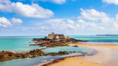 Tarihi Fort National 'ın Saint-Malo, Brittany, Fransa' daki kayalık adasındaki panoramik manzarası. Su birikintileri, kumlu plajlar ve parlak mavi gökyüzü ile alçak sularda yakalandılar.