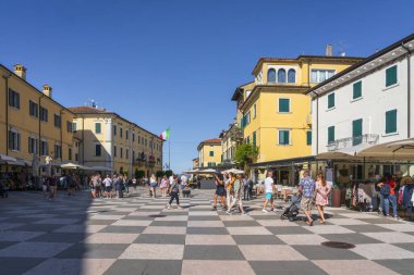 LAZISE, VENETO - İTALYA 6 Eylül 2025 Lazise 'deki Piazza Vittorio Emanuele' de yürüyen insanlar. Garda Gölü, Veneto, İtalya 'da kareli kaldırımı olan tarihi şehir merkezi.