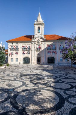 Saat kulesiyle Aveiro Belediye Binası 'nın manzarası. Geleneksel Portekiz kaldırımı, Calcada Portuguesa, berrak mavi gökyüzünün altında.