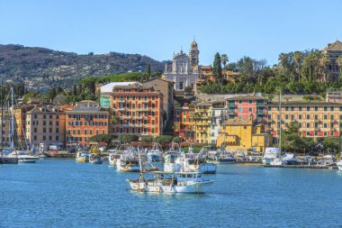 Santa Margherita Ligure limanının manzarası. Geleneksel balıkçı tekneleri, renkli tarihi binalar, ve tepedeki kilise, Liguria, İtalya