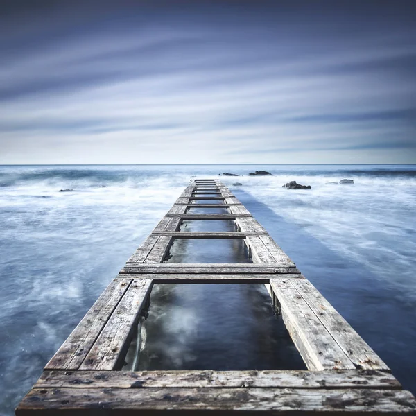 Muelle de madera o embarcadero en un océano azul. Exposición larga — Foto de Stock