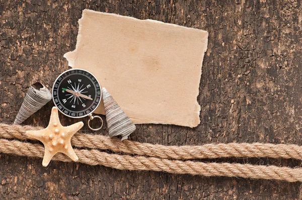 Papír, az iránytű, a kötél és a kagyló a régi, fából készült háttér — Stock Fotó