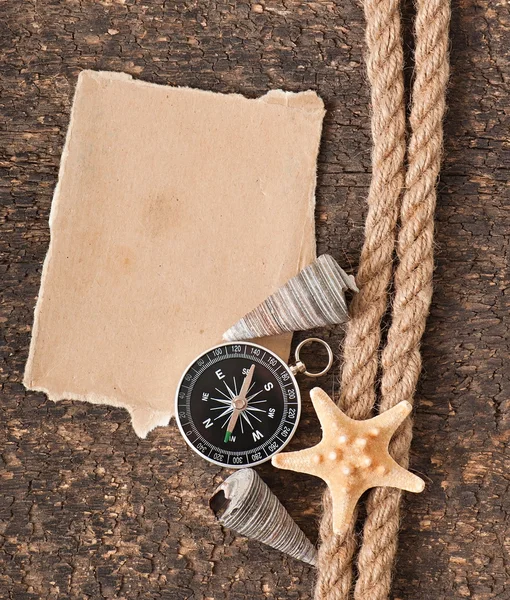 Papier, boussole, corde et coquillage sur le vieux fond en bois — Photo