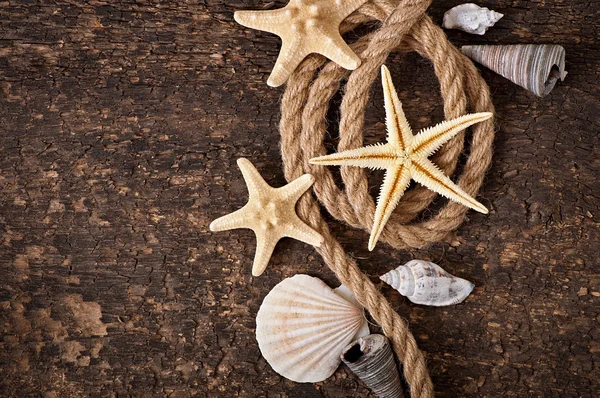 Starfish, seashells and rope on old wooden background — Stock Photo, Image