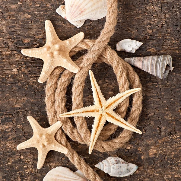 Hvězdice, mušle a provaz na staré dřevěné pozadí — Stock fotografie