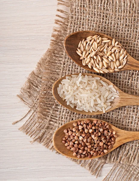 Wooden spoons and buckwheat, rice and oats — Stock Photo, Image