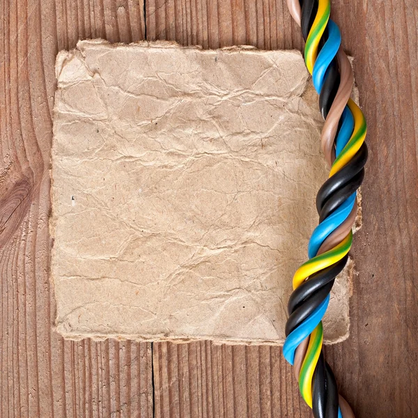 Papier et câble électrique sur le vieux fond en bois — Photo