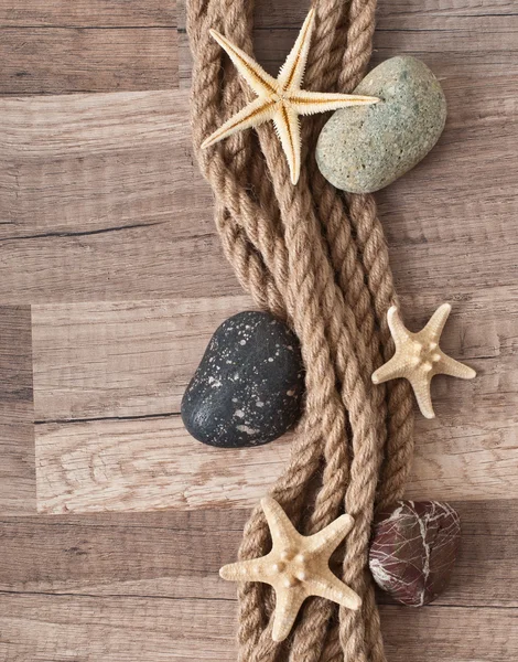 Cuerda, estrellas de mar, piedras de mar sobre el viejo fondo de madera —  Fotos de Stock