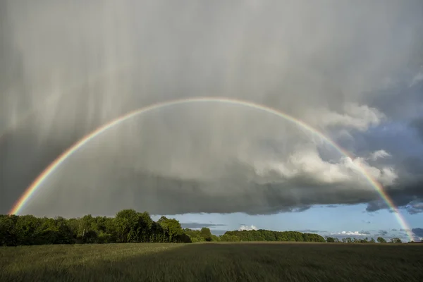 Double rainbow over a field with sunshine and rain — Stock Photo, Image