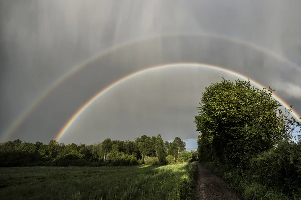 Espectacular arco iris doble con sol y lluvia —  Fotos de Stock