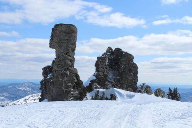 Camels rocks on the top of the Green mountain of the Sheregesh ski resort against the background of a clear winter sky with clouds