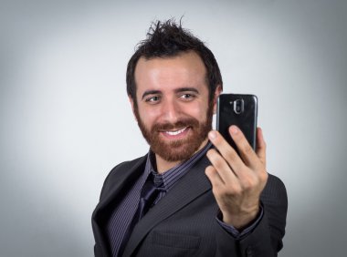 İşadamı gülümseyen onun smartphone bir selfie almak için kullanıyor