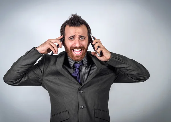 Estressado jovem homem de negócios gritando para seus 2 telefones — Fotografia de Stock