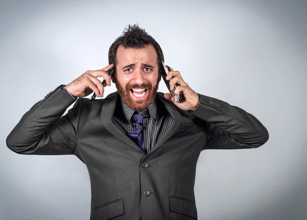 Hombre de negocios joven estresado gritando a sus 2 teléfonos Imagen De Stock