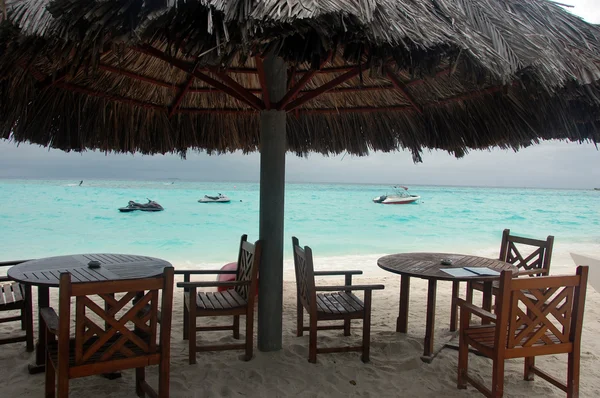 Καρέκλες και τραπέζια κάτω από μεγάλη ομπρέλα στην παραλία — Φωτογραφία Αρχείου