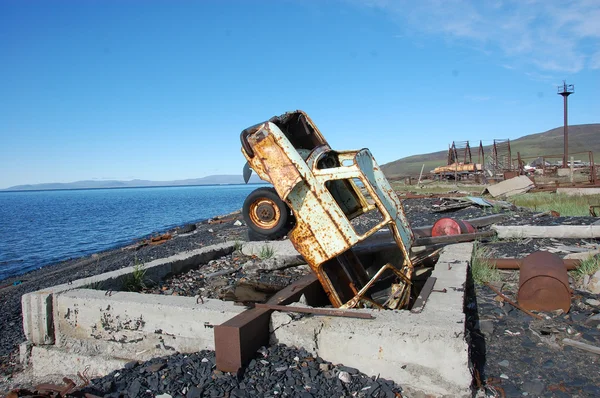 Velho carro enferrujado abandonado quebrado de cabeça para baixo na costa do mar — Fotografia de Stock