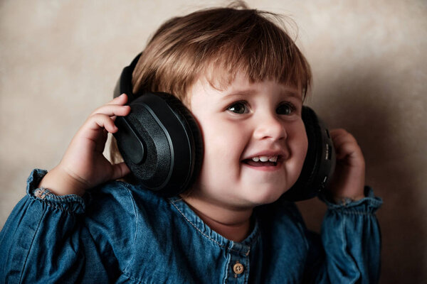 Cute little girl in big black headphones listening to music. Adorable Baby Girl smiling with headphones.