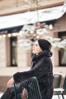 Kış moda portresi: kürklü şık bayan. Kışın açık havada kürklü gülümseyen bir kadının portresi. Dışarıda yalnız bir kadın, karlı, soğuk bir gün.