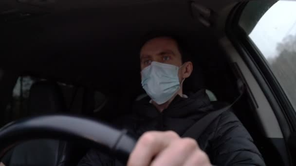 The driver in a medical mask is driving a car — Stock Video