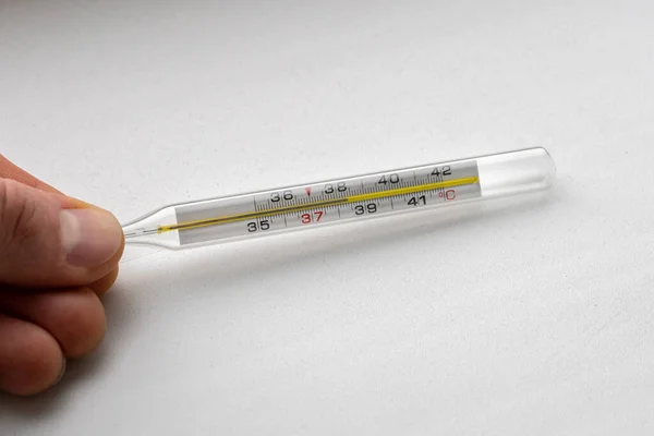 Thermometer with high temperature in a hand close-up.