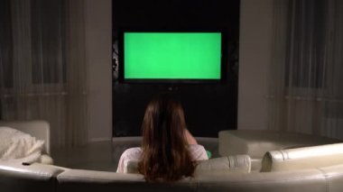 Kız televizyonu yeşil ekran ile açar ve onu izler..