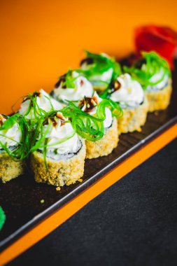 Somon ve yılan balıklı rulo siyah bir tabakta güzel bir sunumla