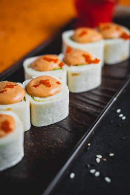 Somon ve yılan balıklı rulo siyah bir tabakta güzel bir sunumla