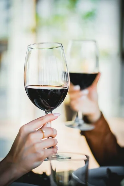 Dos vasos de vino tomados de la mano en un restaurante Imagen de stock