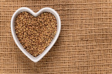 Kalp şeklindeki mercimek arka planda ve dokuda. Üst görünüm.