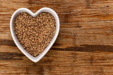 Kalp şeklindeki mercimek arka planda ve dokuda. Üst görünüm.