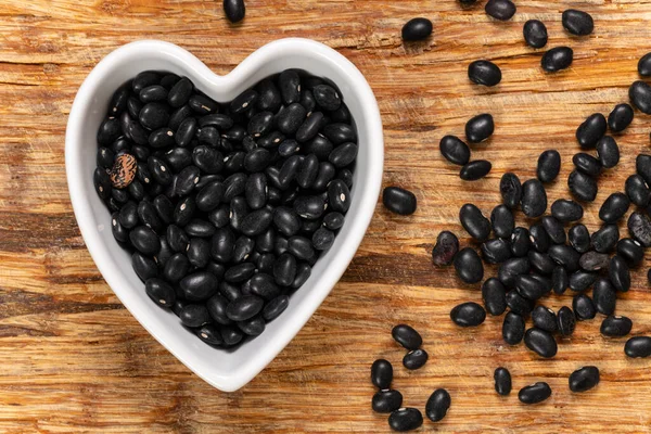 Black kidney beans in a heart-shaped bowl background and texture. Top view.