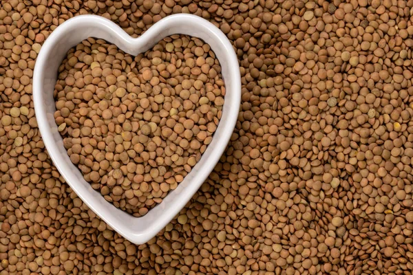 Lentils in a heart shaped bowl background and texture. Top view. — Stock Image Lentils Heart Shaped Bowl Background Texture Top View Royalty Free Stock Photos