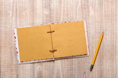 Ahşap masa üzerinde kurşun kalem olan boş bir kağıt defter. Üst görünüm.