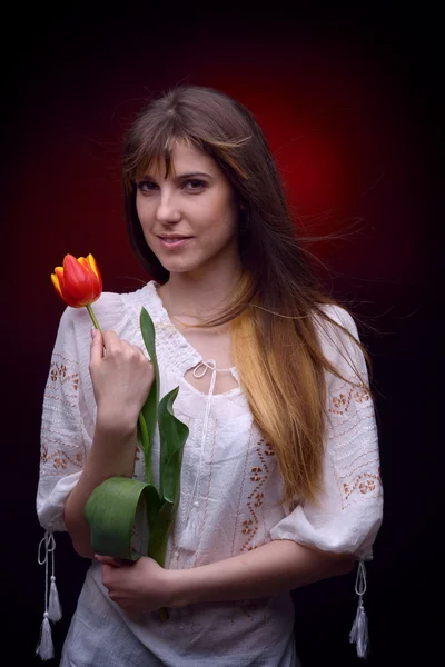 Junge hübsche Frau mit roter Tulpe — Stockfoto