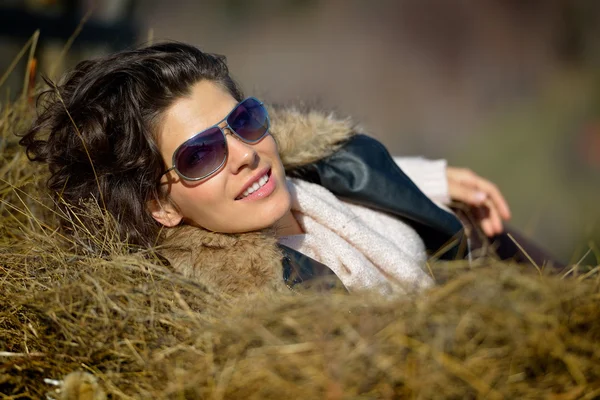 Beautiful young woman relaxing on hay stack in autumn — Stock Photo, Image