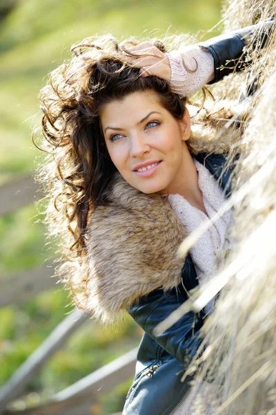 Beautiful young woman relaxing under a hay stack in autumn — Stock Photo, Image