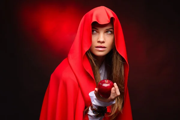 Όμορφη γυναίκα με κόκκινο μανδύα, κρατώντας το μήλο στο χέρι της — Φωτογραφία Αρχείου