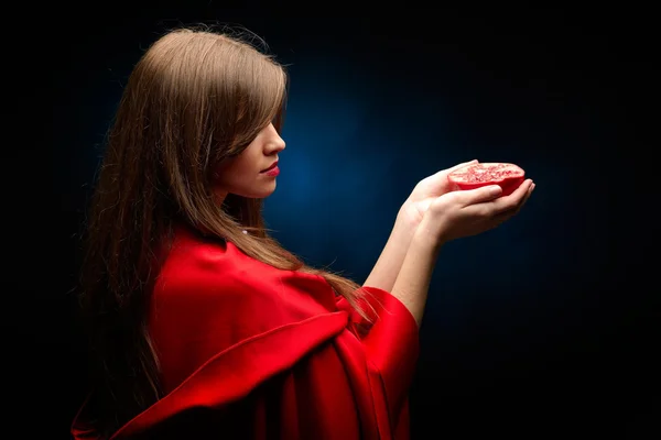 Mooie vrouw met rode mantel houden granaatappel — Stockfoto