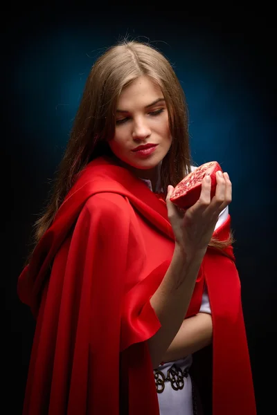 Beautiful woman with red cloak holding pomegranate — Stock Photo, Image