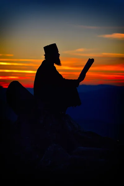 Silhouet van priester lezen in de zonsondergang licht — Stockfoto