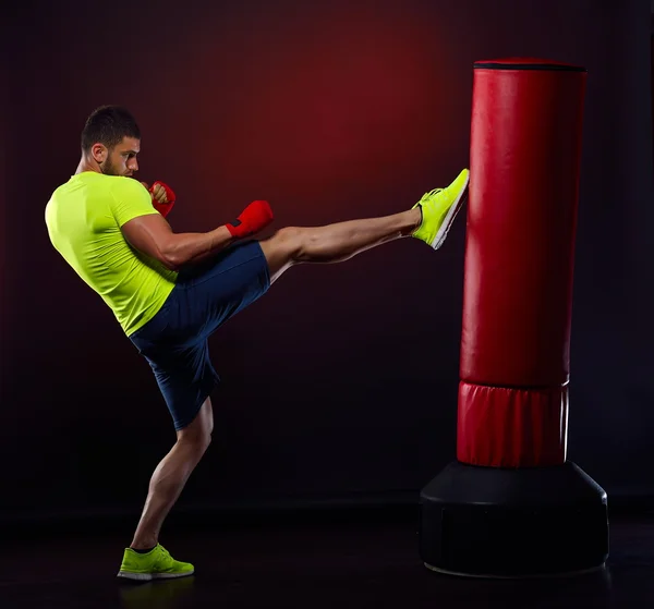 Jovem homem exercitando saco de boxe no estúdio — Fotografia de Stock