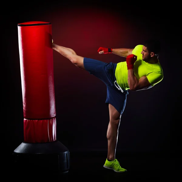 Jovem homem exercitando saco de boxe no estúdio — Fotografia de Stock