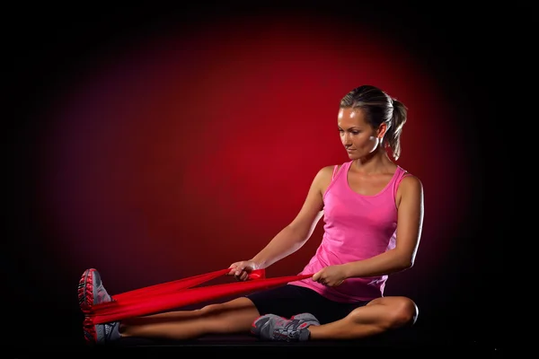 Giovane donna che si allena con elastico in palestra — Foto Stock