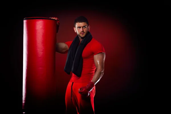 Jovem homem de pé por boxe saco no estúdio — Fotografia de Stock