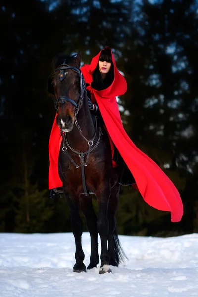 Mulher bonita com manto vermelho com cavalo ao ar livre no inverno — Fotografia de Stock